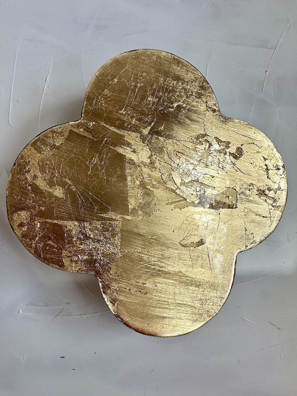 Gold four-leaf clover-shaped object on a white background